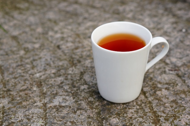 Primer plano de té en una taza blanca en el suelo bajo las luces con un fondo borroso