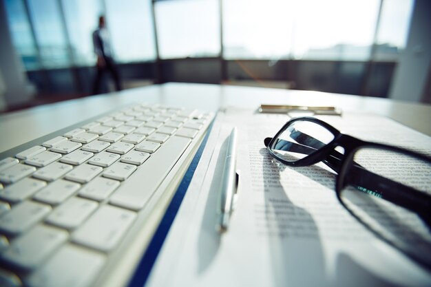 Primer plano de teclado y gafas en la mesa