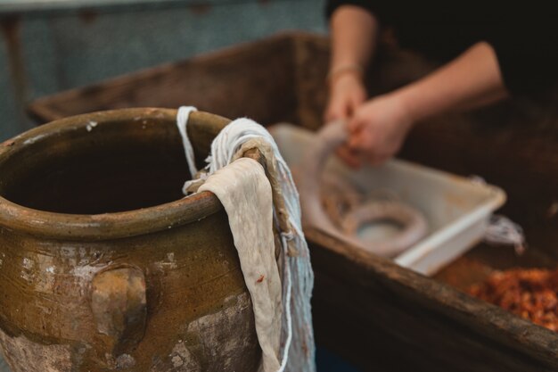 Primer plano de una tela en una olla de barro con una persona que prepara una kielbasa en la borrosa