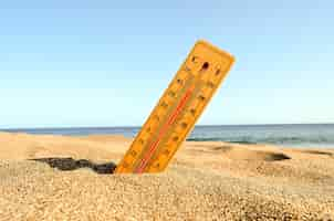 Foto gratuita un primer plano de un termómetro en la arena de la playa