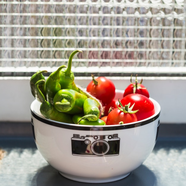 Primer plano de tomates cherry y chiles verdes en un tazón