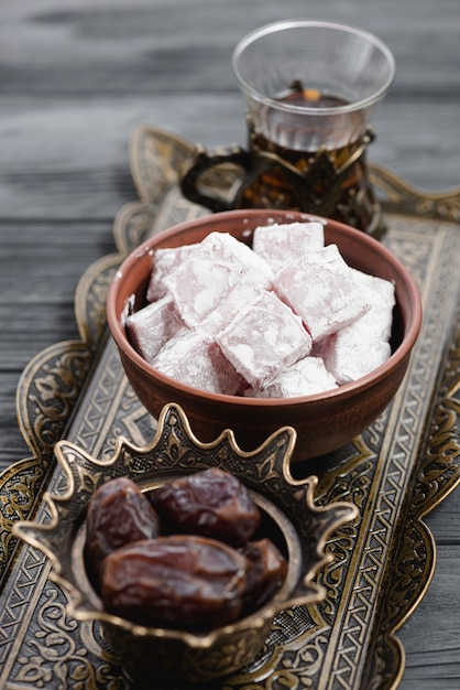Primer plano de la tradicional delicia turca lukum; Fechas y té en bandeja metálica.