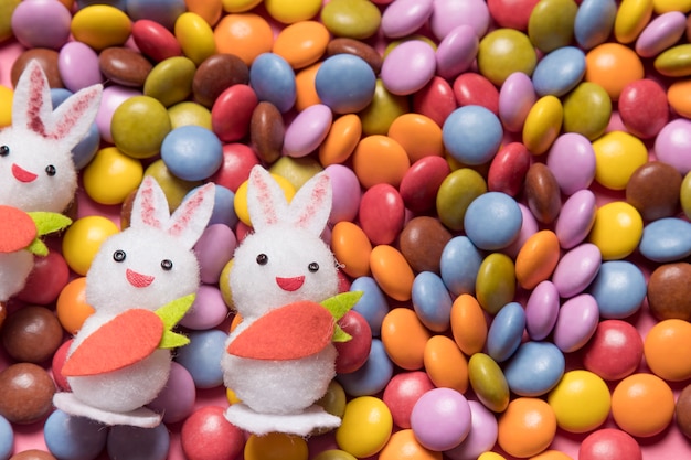 Primer plano de tres conejitos blancos sobre los caramelos de gemas de colores