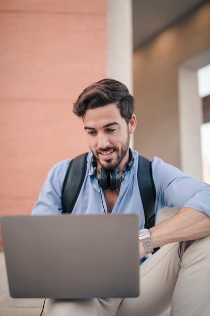 Primer plano de un turista masculino feliz usando la computadora portátil