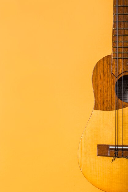 Primer plano de ukelele de madera sobre fondo amarillo