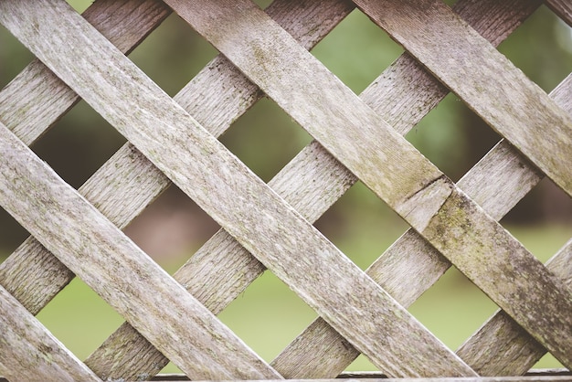 Primer plano de una valla entrecruzada de madera con un borroso