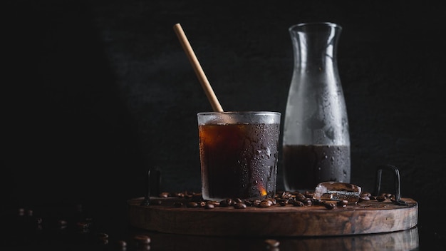 Primer plano de un vaso de café frío con una botella en el fondo