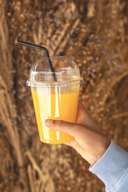 Primer plano un vaso de jugo de naranja en una mano femenina