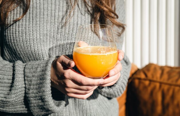 Primer plano un vaso de jugo de naranja en manos femeninas