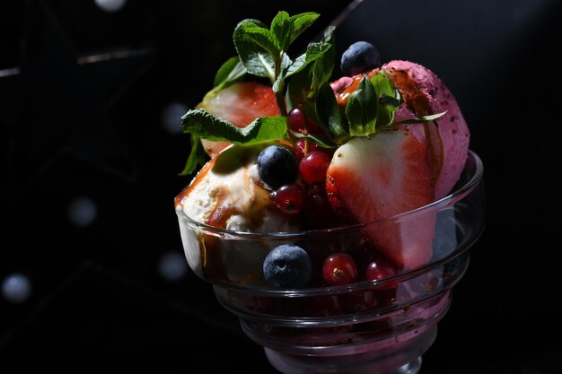 Primer plano de un vaso de postre de chocolate con diferentes bayas y frutas