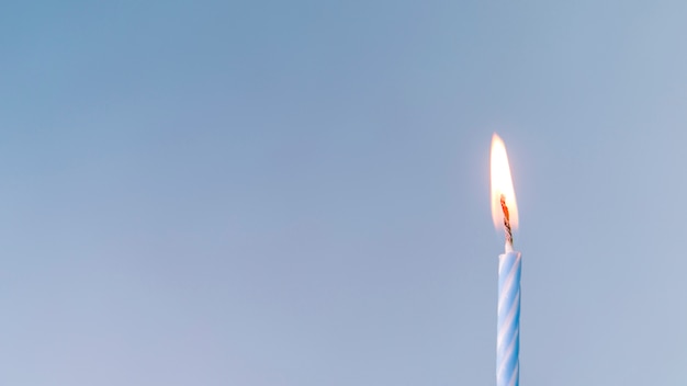 Primer plano de una vela iluminada sobre fondo azul