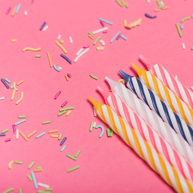 Primer plano de velas a rayas con chispitas de colores sobre fondo rosa