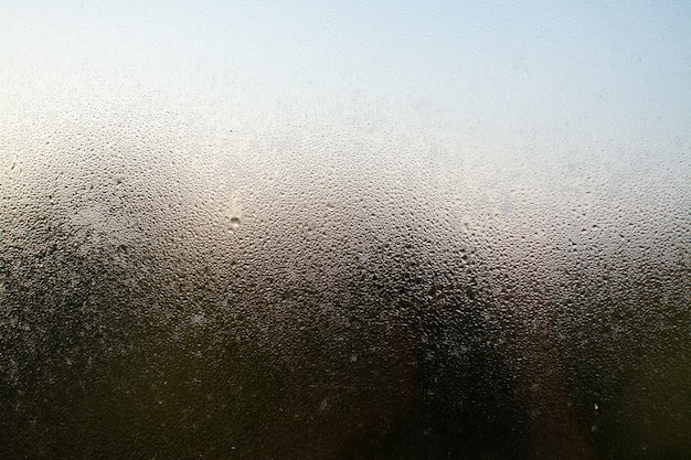 Un primer plano de una ventana brumosa con gotas de agua