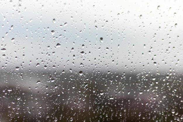 Primer plano de una ventana en un día lluvioso, gotas de lluvia rodando por la ventana
