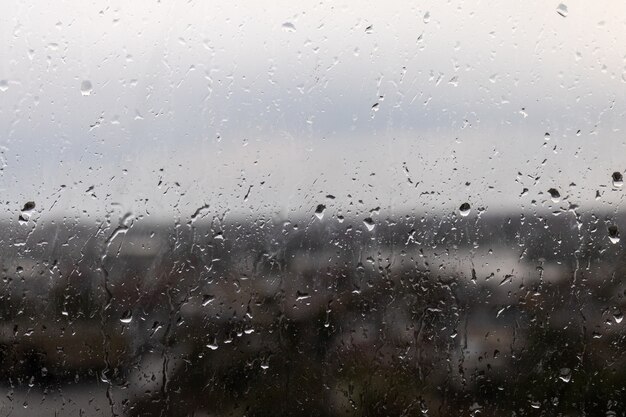 Primer plano de una ventana en un día lluvioso y sombrío, gotas de lluvia rodando por la ventana