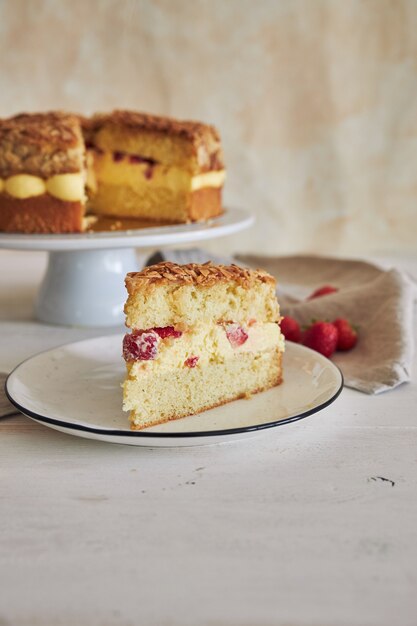 Primer plano vertical de la deliciosa tarta de crema de vainilla con fresas dentro de una mesa blanca