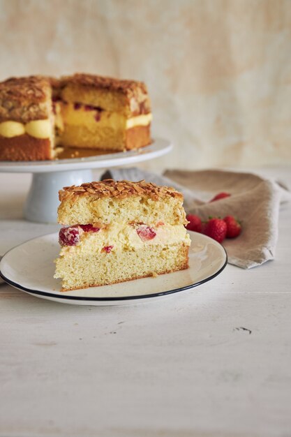 Primer plano vertical de la deliciosa tarta de crema de vainilla con fresas dentro de una mesa blanca