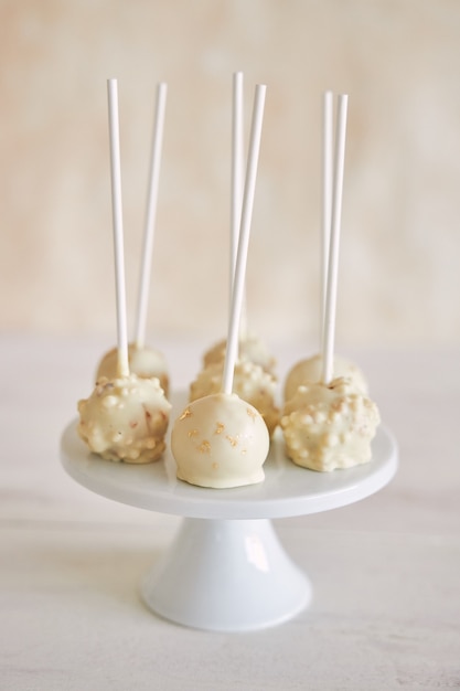 Primer plano vertical de delicioso pastel blanco aparece sobre un fondo blanco y una mesa de madera