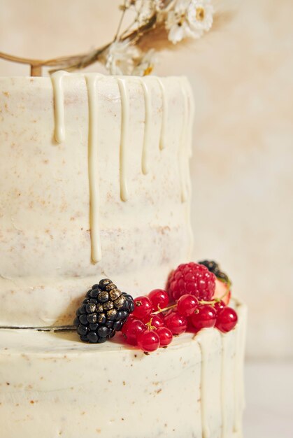 Primer plano vertical de un delicioso pastel de bodas decorado con frutas y bayas frescas