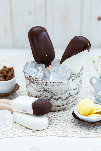 Primer plano vertical de helado vegano en un palo en un recipiente con cubitos de hielo