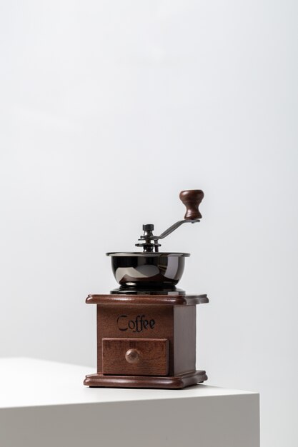 Primer plano vertical de un mini molinillo de café vintage sobre la mesa bajo las luces