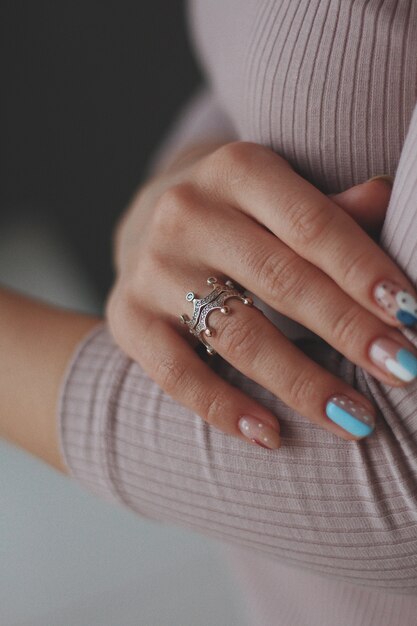 Primer plano vertical de una mujer con bonitas uñas vistiendo un hermoso anillo de plata