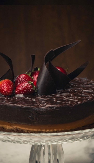 Primer plano vertical de un pastel de chocolate con fresas en la parte superior