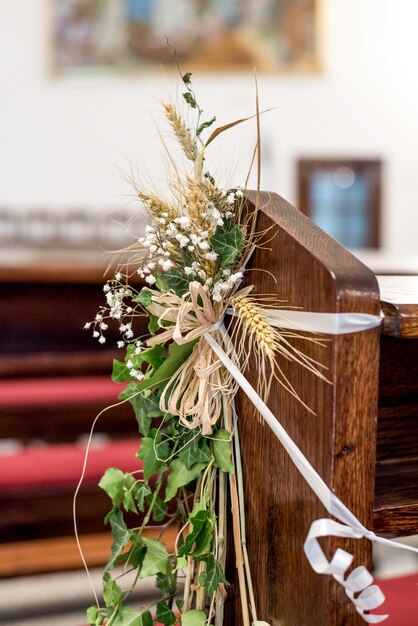 Primer plano vertical de plantas decorativas en una silla de boda de madera