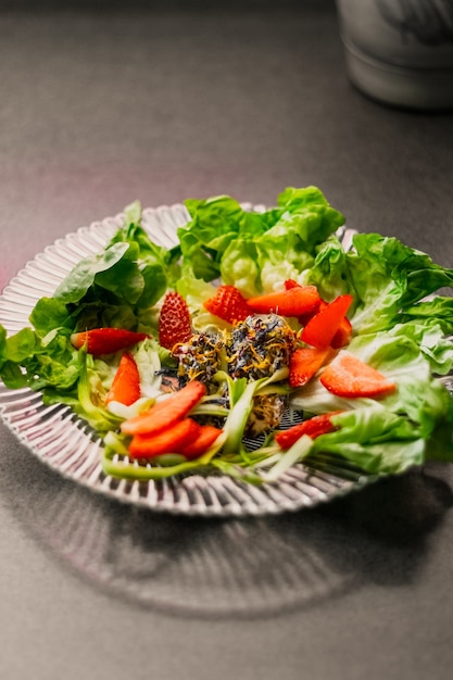 Primer plano vertical de un plato vegetariano con lechuga y fresas.