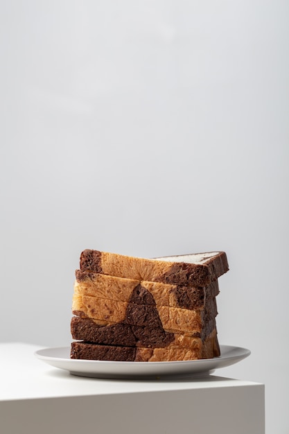 Primer plano vertical de rebanadas de pan blanco mezclado con chocolate en un plato sobre la mesa bajo las luces