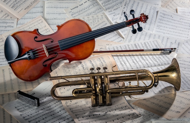 Primer plano de un violín y una trompeta en hojas de notas bajo las luces