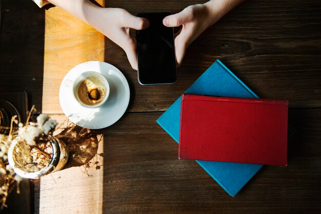 Primer plano de vista aérea de las manos con el teléfono móvil en café café en la mesa de madera