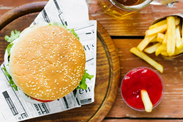 Primer plano de la vista superior de hamburguesa y papas fritas en tablero de madera