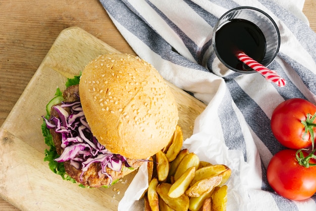 Primer plano de la vista superior de hamburguesa y papas fritas en tablero de madera