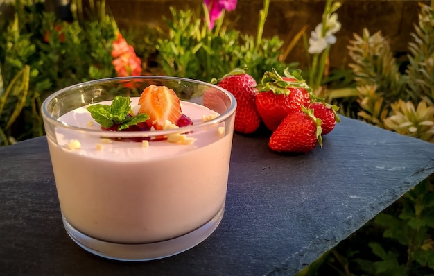 Primer plano de yogur de fresa con fresas en el cuadro negro