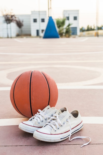 Primer plano de zapatillas y baloncesto en pista.