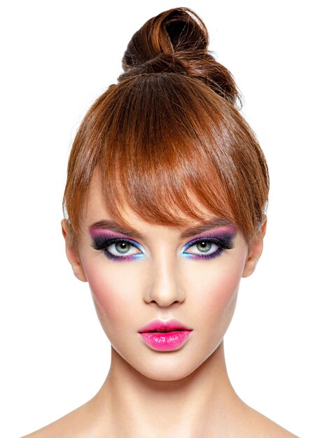 Primer rostro de una mujer hermosa con maquillaje vivo brillante. Modelo de moda con maquillaje de ojos creativo - aislado en blanco. Chica con cabello pelirrojo. Peinado corto con flecos