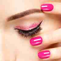 Foto gratuita primer rostro de mujer con uñas rosadas cerca de los ojos. uñas con manicura rosa.