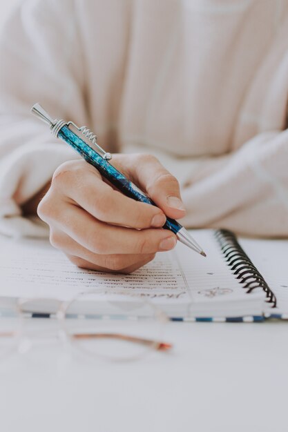 Primer selectivo vertical de una escritura femenina en un cuaderno con un bolígrafo azul