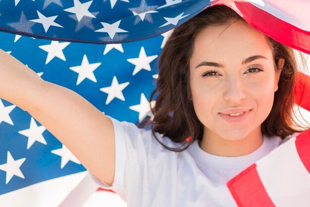 Primer sonriente mujer sosteniendo gran bandera de Estados Unidos