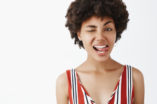 Foto gratuita primer tiro de afroamericano coqueto, emotivo y juguetón con peinado afro sacando la lengua y guiñando un ojo