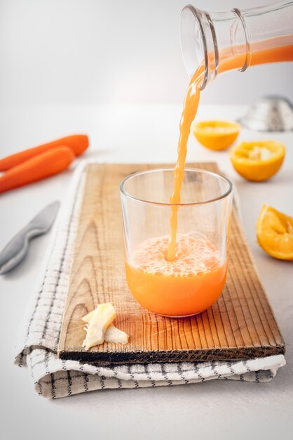 Primer vaso de jugo de naranja recién exprimido estudiando detenidamente de una botella transparente