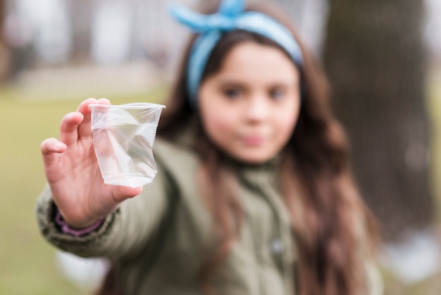 Primer vaso de plástico con niña desenfocada