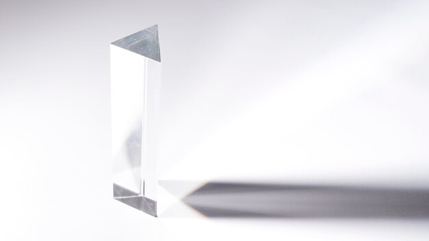 Prisma de cristal transparente con sombra oscura sobre fondo blanco