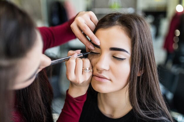 Procedimiento de párpados para modelo bonita de pelo largo en salón de belleza