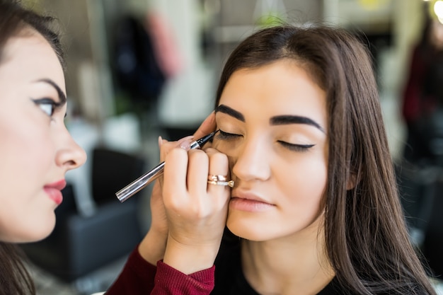 Procedimiento de párpados para modelo sonriente de pelo largo en salón de belleza