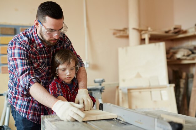 Procesando pieza de trabajo, padre e hijo trabajando con madera