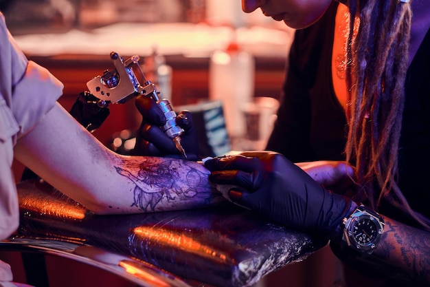 Foto gratuita proceso de creación de un nuevo tatuaje para una mujer joven por parte de un tatuador experimentado en el estudio.