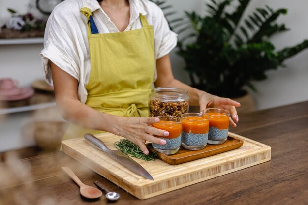 Proceso de elaboración del pudín de chía. Capas de diferentes colores hechas de leche de almendras, semillas de chía, extracto de súper alimento de espirulina azul y mermelada de papaya y mango.