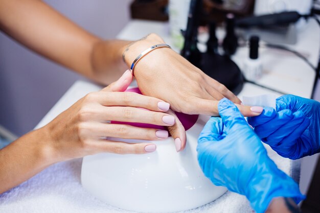 Proceso de fabricación de tratamiento de uñas de manos femeninas hermosas Taladro de lima de uñas profesional en acción Concepto de cuidado de la belleza y las manos